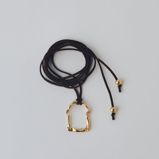 Brown cord necklace with a gold pendant on a light gray background