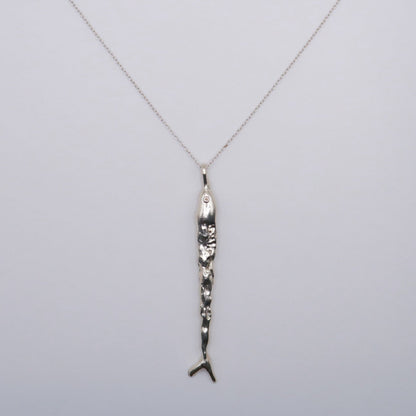 Silver necklace with a fish pendant in silver  on a light gray background