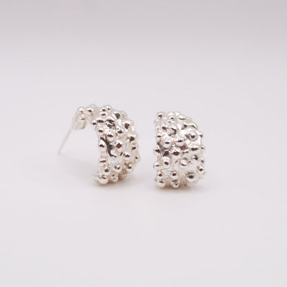 Pair of silver hoop earrings on a light gray background