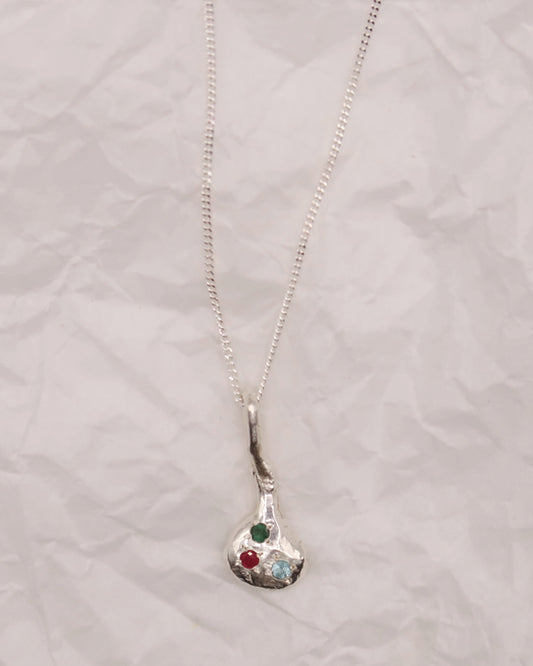 Silver necklace with a pendant featuring colorful stones on a light gray textured background