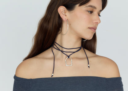 Woman wearing a layered neck choker and hoop earrings on a plain background