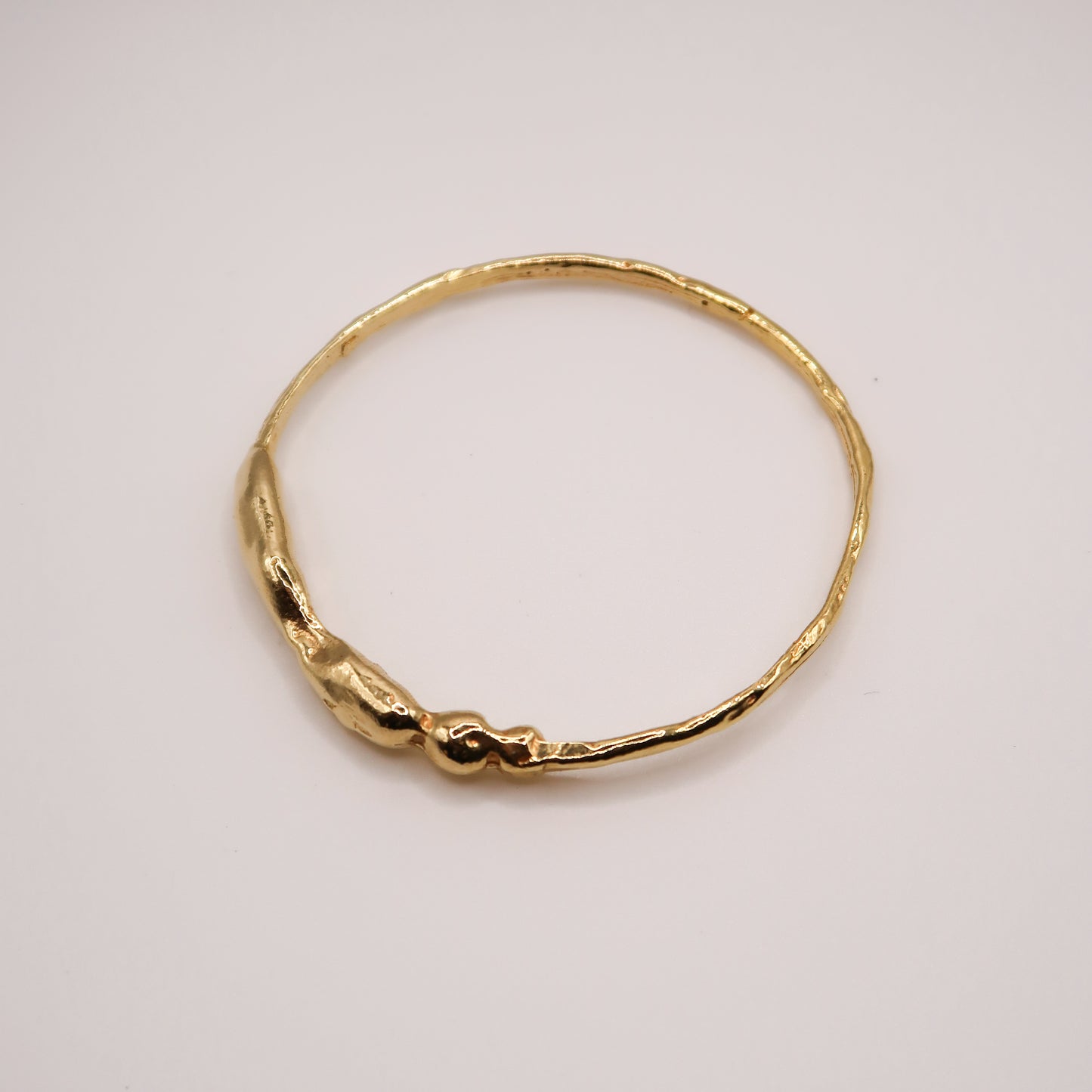 Gold bracelet on a light gray background