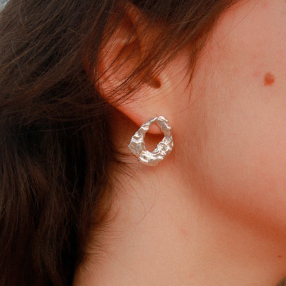 Close-up of a silver hoop earring worn by a person with dark hair.