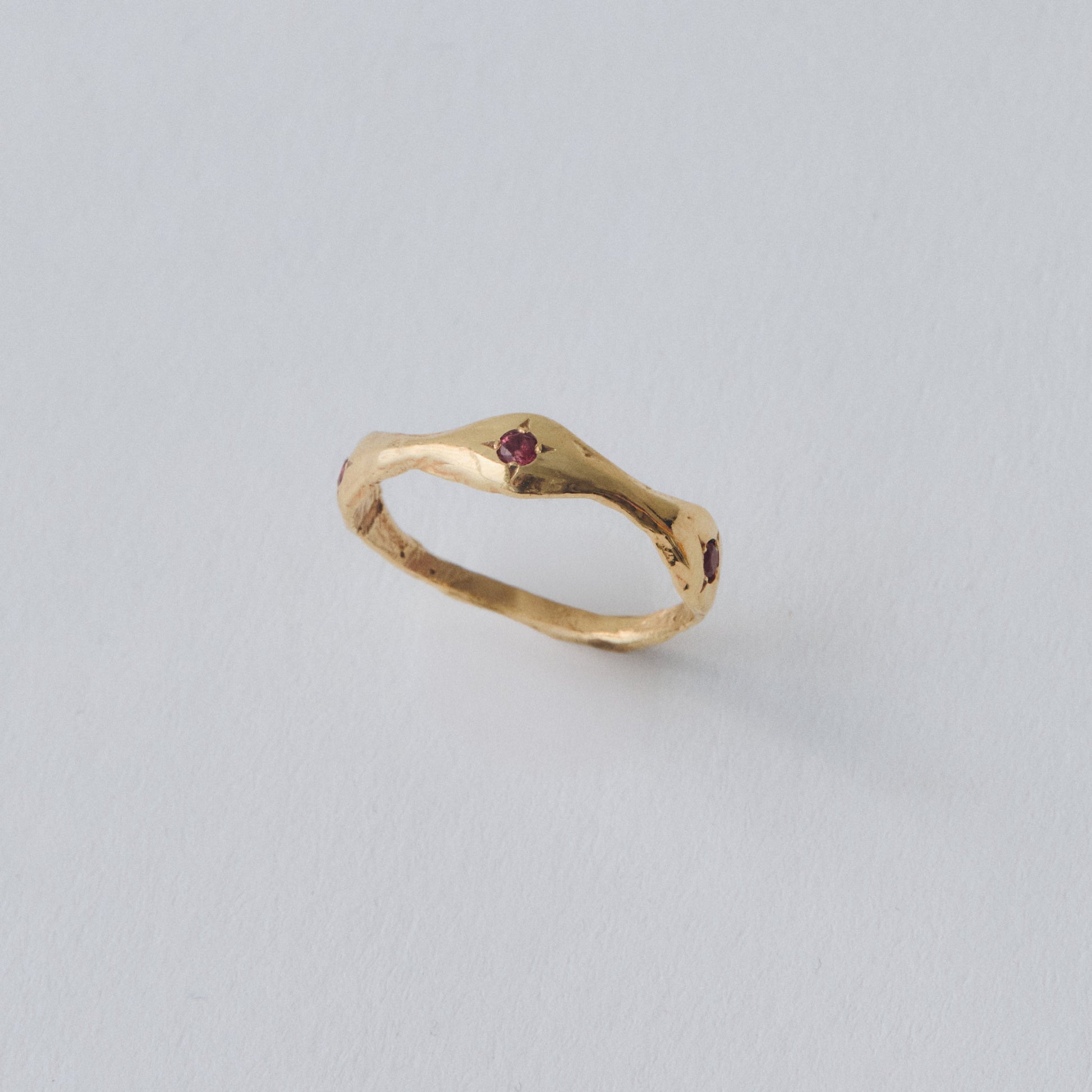 Gold ring with a small gemstone on a light gray background