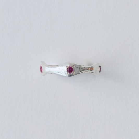 Silver ring with a red gemstone on a light gray background