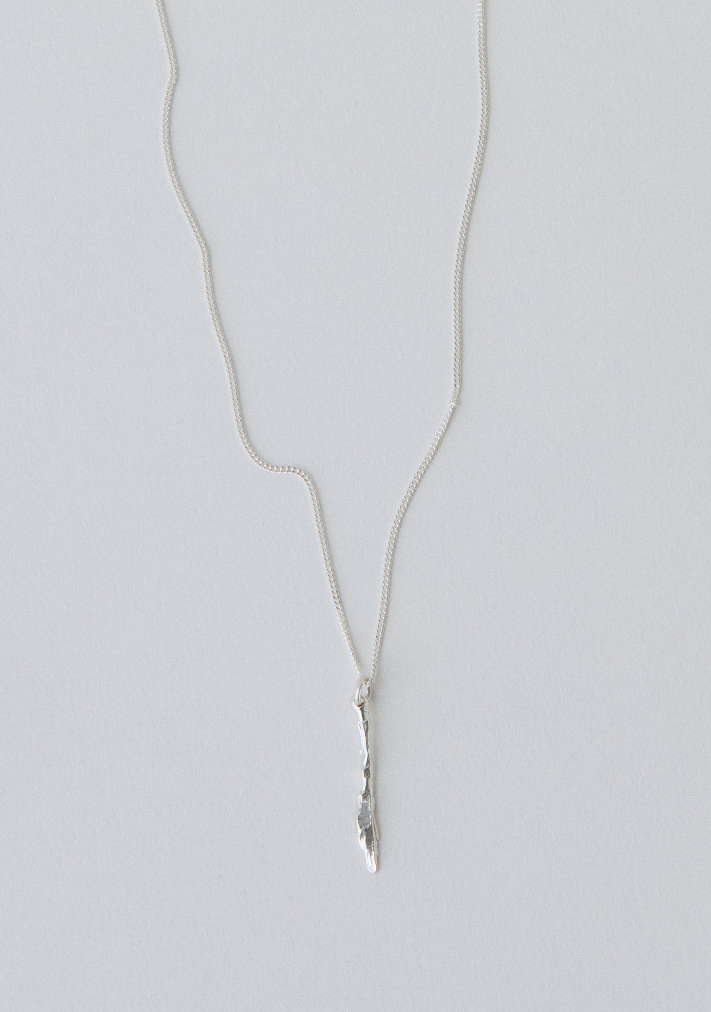 Silver necklace with a knife pendant on a light gray background