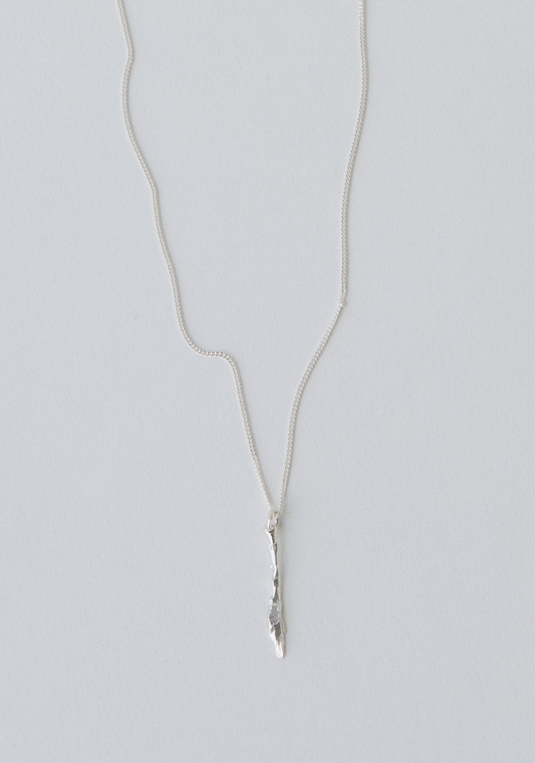 Silver necklace with a knife pendant on a light gray background
