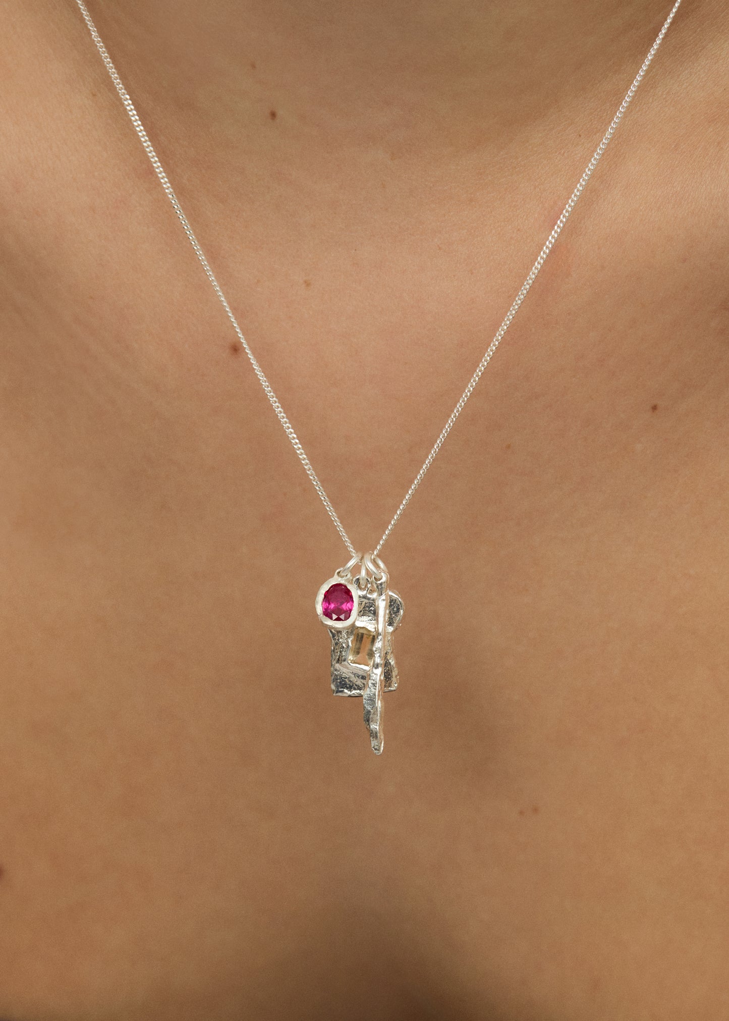 Silver necklace with a pink gemstone pendant on a person's neck
