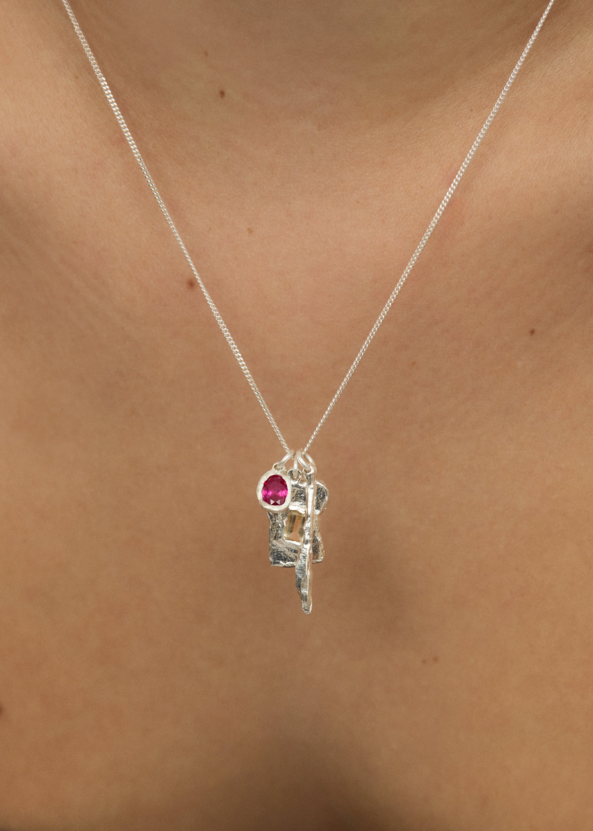 Silver necklace with a pink gemstone pendant on a person's neck