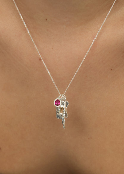 Silver necklace with a pink gemstone pendant on a person's neck